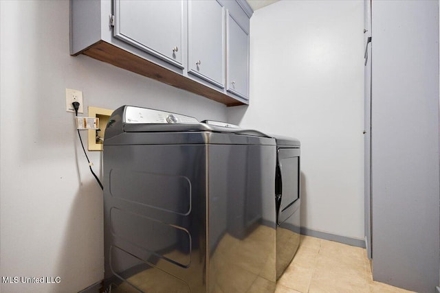 washroom featuring cabinet space, washer and dryer, baseboards, and light tile patterned floors