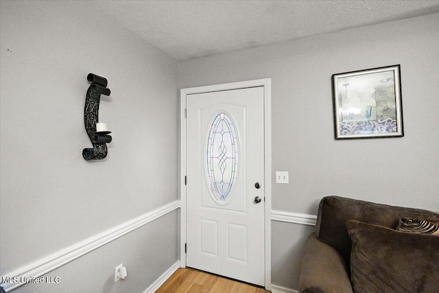 entrance foyer with light wood-style flooring, baseboards, and a textured ceiling