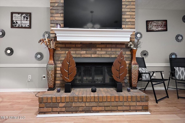 detailed view of a fireplace, wood finished floors, and baseboards