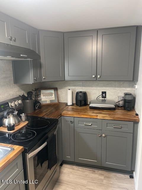 kitchen with butcher block counters, stainless steel electric stove, gray cabinetry, and light wood-type flooring