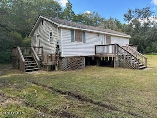 rear view of property featuring a yard and a deck