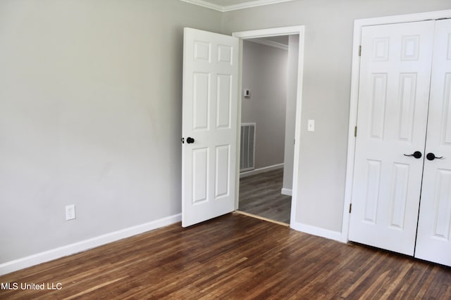 unfurnished bedroom featuring a closet, ornamental molding, and dark hardwood / wood-style flooring