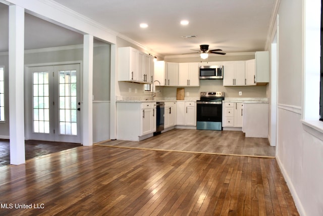 kitchen with stainless steel appliances, ornamental molding, dark hardwood / wood-style flooring, and white cabinets