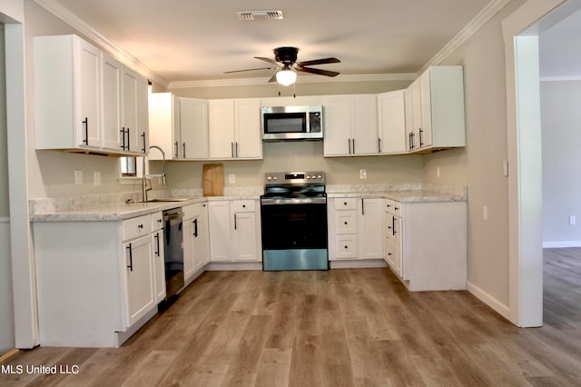 kitchen with white cabinetry, appliances with stainless steel finishes, sink, and ornamental molding