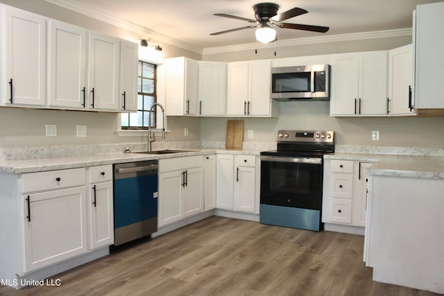 kitchen featuring white cabinets, appliances with stainless steel finishes, hardwood / wood-style flooring, crown molding, and sink