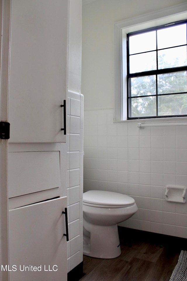 bathroom featuring tile walls, hardwood / wood-style floors, and toilet