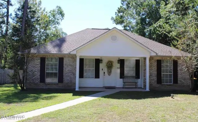 view of front facade featuring covered porch, brick siding, roof with shingles, and a front yard