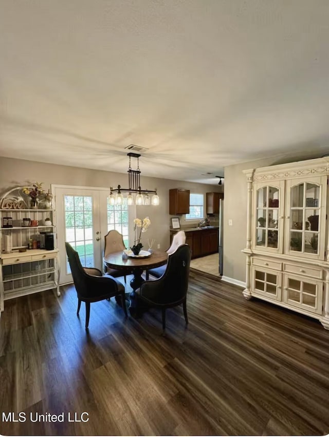 dining space with baseboards, dark wood-type flooring, visible vents, and a healthy amount of sunlight