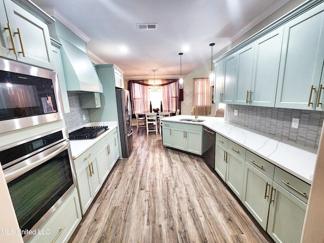 kitchen with light hardwood / wood-style flooring, hanging light fixtures, sink, appliances with stainless steel finishes, and light stone counters