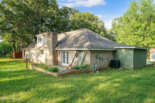 back of property with cooling unit, a patio, french doors, a chimney, and a lawn