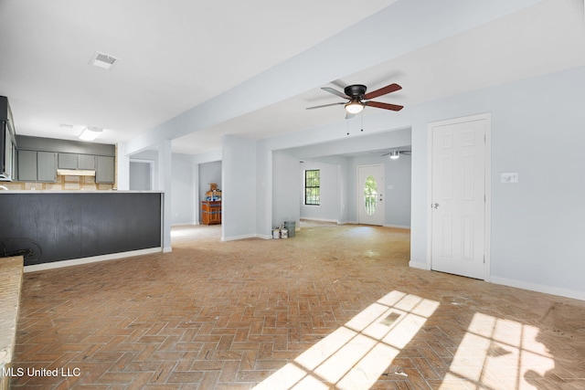 unfurnished living room with a ceiling fan, baseboards, visible vents, and brick floor
