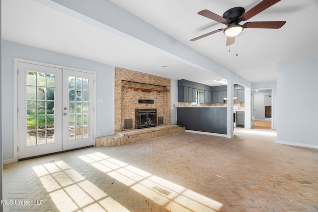 unfurnished living room featuring french doors, a ceiling fan, baseboards, and a fireplace