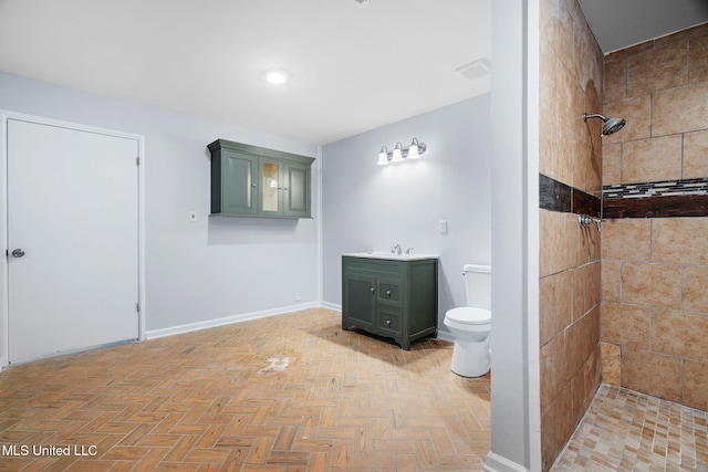 full bath featuring a tile shower, vanity, baseboards, toilet, and recessed lighting