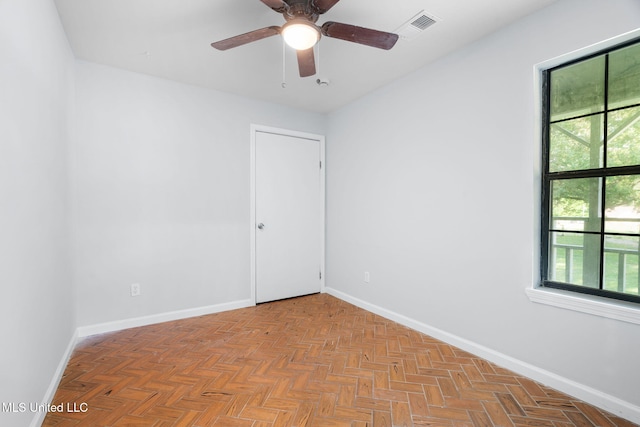 empty room with baseboards, ceiling fan, visible vents, and a wealth of natural light