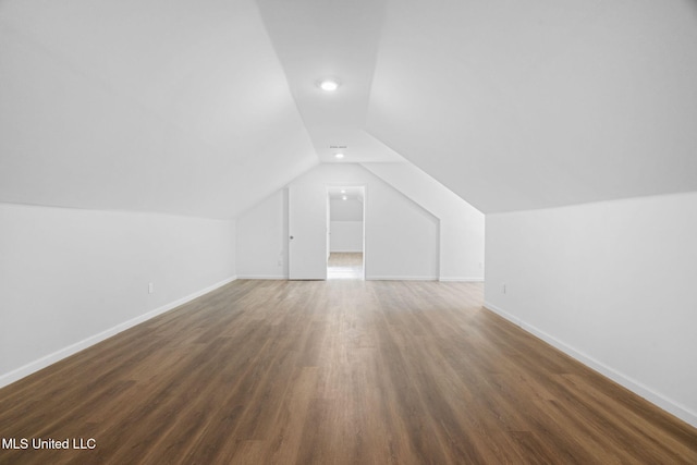 additional living space featuring baseboards, wood finished floors, and lofted ceiling