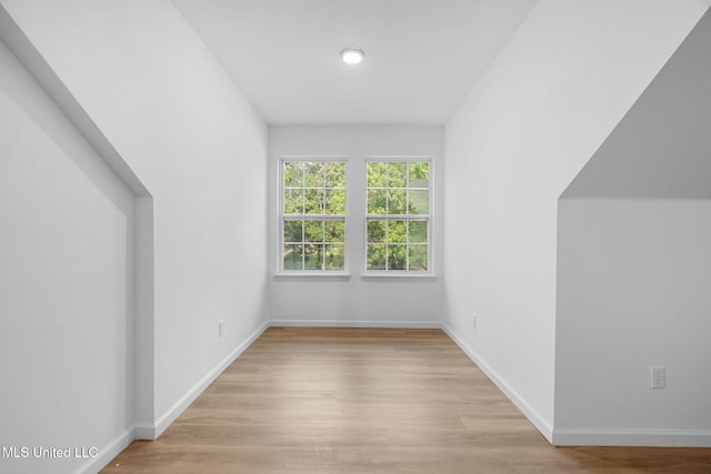 additional living space featuring baseboards and light wood finished floors