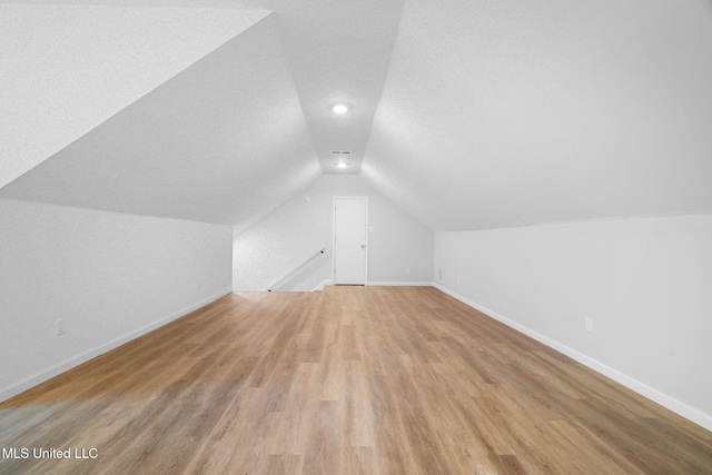 additional living space with baseboards, recessed lighting, light wood-style floors, and lofted ceiling