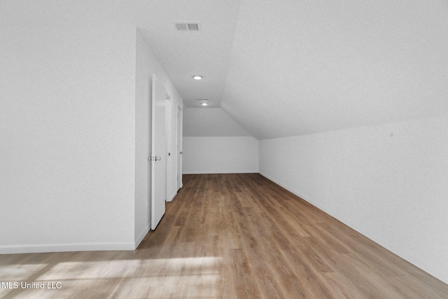 additional living space featuring vaulted ceiling, recessed lighting, wood finished floors, and visible vents
