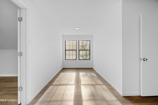 hall with baseboards and wood finished floors