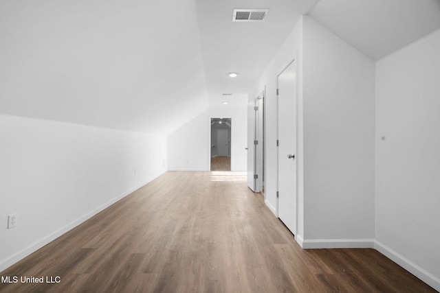 additional living space featuring baseboards, lofted ceiling, wood finished floors, and visible vents