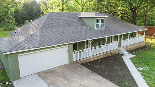 country-style home with a garage, a front lawn, covered porch, roof with shingles, and driveway