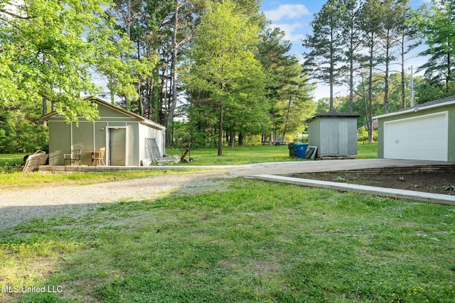 view of yard featuring a detached garage, a storage unit, and an outbuilding