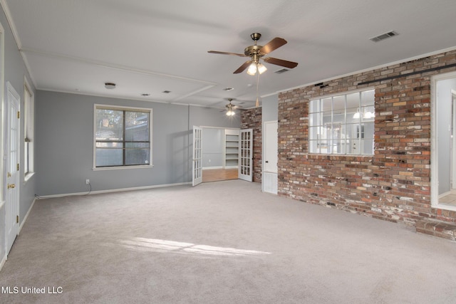 empty room featuring carpet floors, brick wall, visible vents, and crown molding