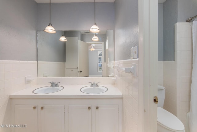 full bathroom featuring a sink, tile walls, and toilet