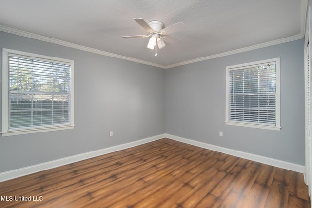 spare room featuring dark wood-style floors, ceiling fan, baseboards, and crown molding