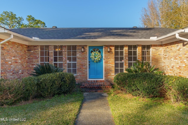 property entrance featuring a shingled roof and brick siding