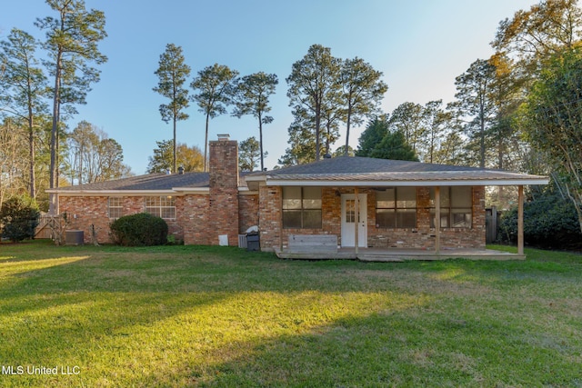 rear view of house featuring brick siding, a yard, a chimney, and central air condition unit