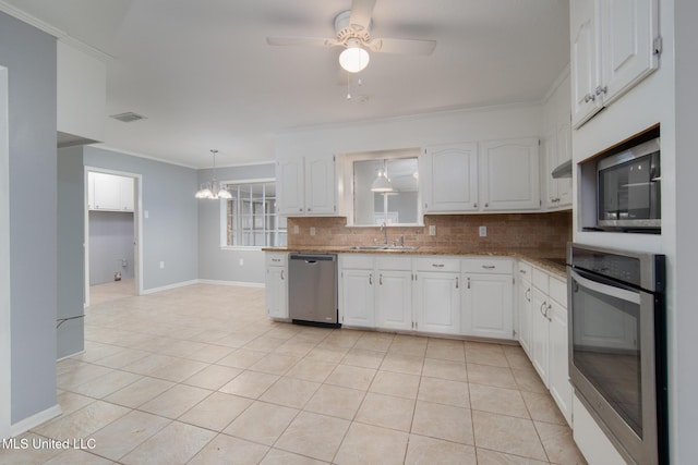 kitchen with light tile patterned flooring, a sink, white cabinetry, appliances with stainless steel finishes, and decorative backsplash