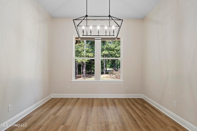 unfurnished dining area featuring a notable chandelier and hardwood / wood-style flooring