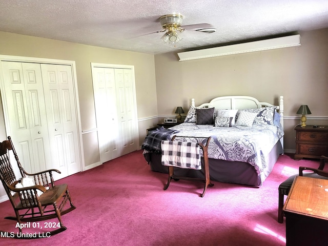 bedroom with ceiling fan, a textured ceiling, carpet floors, and two closets