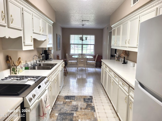 kitchen with hanging light fixtures, stainless steel appliances, sink, a notable chandelier, and a textured ceiling