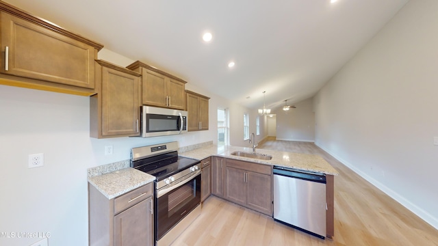 kitchen featuring appliances with stainless steel finishes, ceiling fan, sink, light hardwood / wood-style floors, and lofted ceiling