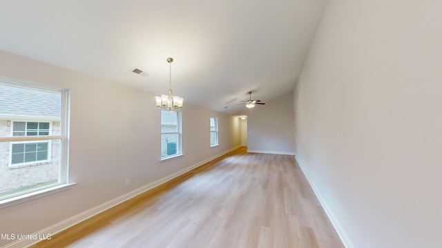 spare room with ceiling fan with notable chandelier and light hardwood / wood-style flooring