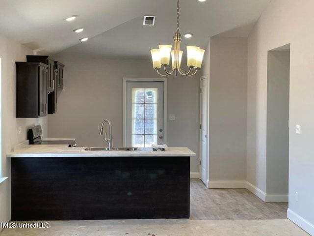 kitchen featuring pendant lighting, sink, stainless steel range oven, kitchen peninsula, and a chandelier