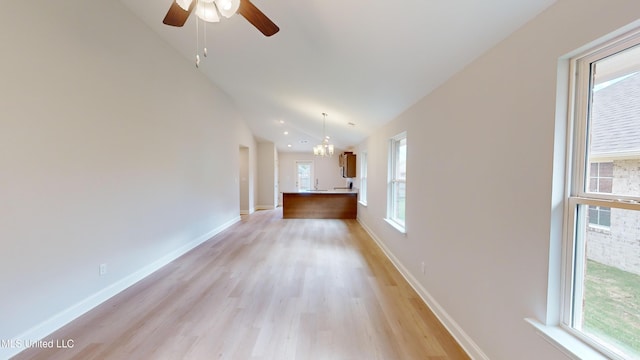 interior space with lofted ceiling, light wood-type flooring, an inviting chandelier, and a healthy amount of sunlight