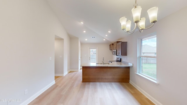 kitchen featuring kitchen peninsula, light wood-type flooring, stainless steel appliances, and hanging light fixtures