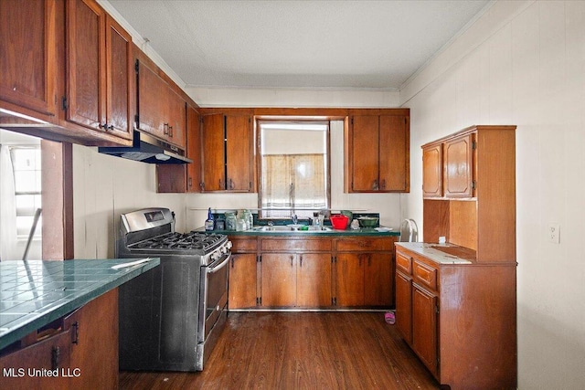 kitchen with under cabinet range hood, brown cabinets, dark wood-style flooring, and stainless steel gas range