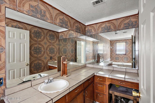 bathroom with vanity, visible vents, wallpapered walls, a textured ceiling, and crown molding