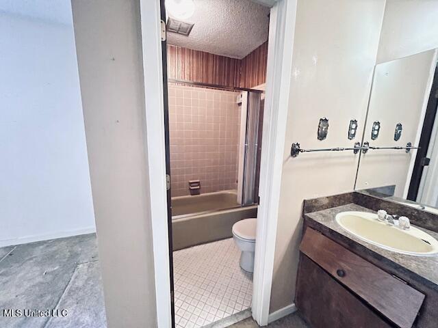 full bathroom featuring tile patterned floors, a textured ceiling, toilet, vanity, and tiled shower / bath