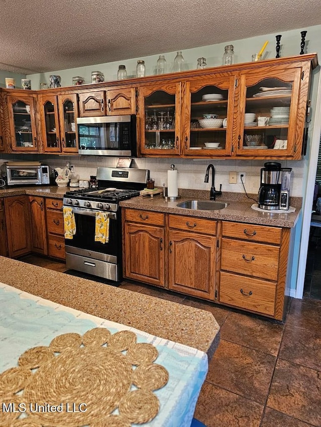 kitchen with tasteful backsplash, sink, stainless steel appliances, and a textured ceiling