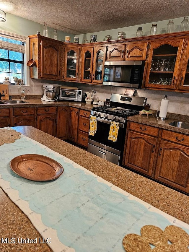 kitchen with sink, a textured ceiling, stainless steel appliances, and backsplash