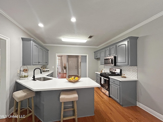 kitchen with backsplash, kitchen peninsula, sink, and appliances with stainless steel finishes