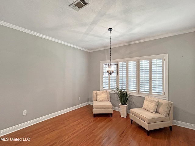 sitting room featuring hardwood / wood-style floors, a notable chandelier, crown molding, and a textured ceiling