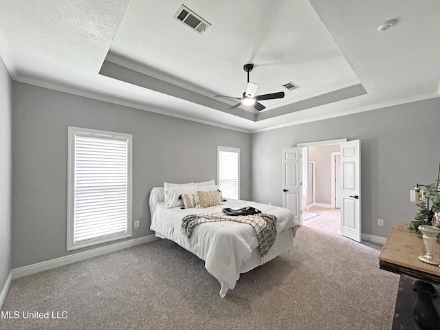 bedroom featuring ceiling fan, a raised ceiling, light colored carpet, and ornamental molding