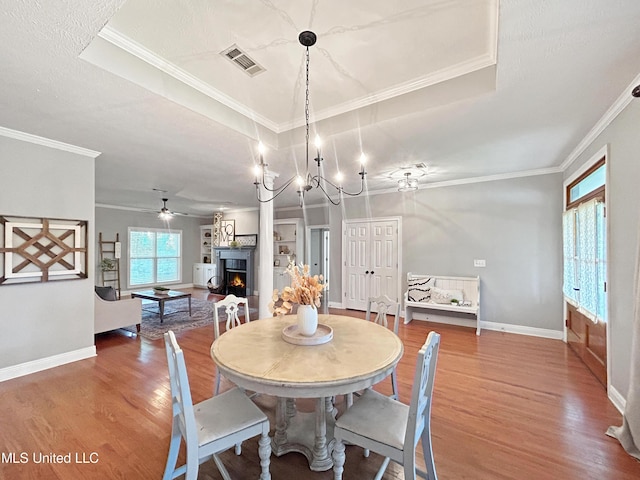 dining room featuring a raised ceiling, crown molding, ceiling fan with notable chandelier, and hardwood / wood-style flooring