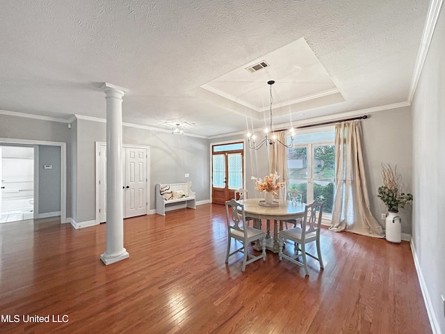 dining area featuring a raised ceiling, crown molding, and ornate columns